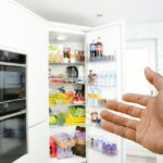 Eine Hand zeigt auf einen Kühlschrank.