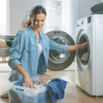 Junge Frau legt Wäsche in den Trockner