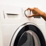 Hand dreht am Einstellungsrad einer Waschmaschine