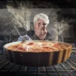 Frau schaut nach einem Auflauf im Ofen