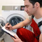 Handwerker macht sich Notizen zu defekter Waschmaschine