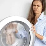 Junge Frau rümpft beim Waschmaschine säubern die Nase